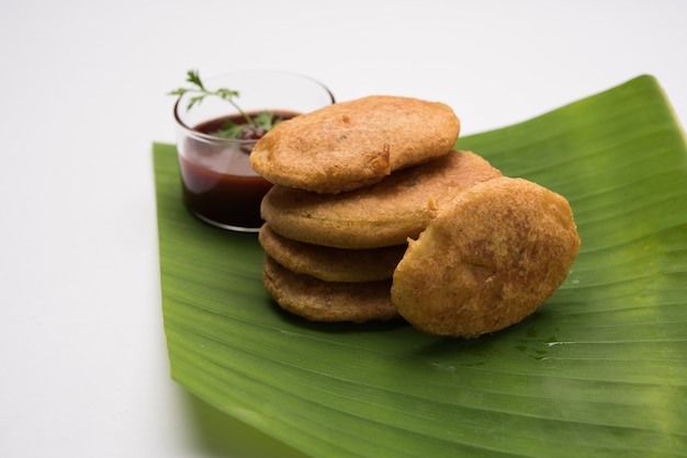 Patata o aloo pakora o pakode o aloo bhajji servido con salsa de tomate, té verde frito frío y caliente, aperitivo indio popular de todos los tiempos, servido sobre hoja de coco fresca, enfoque selectivo
