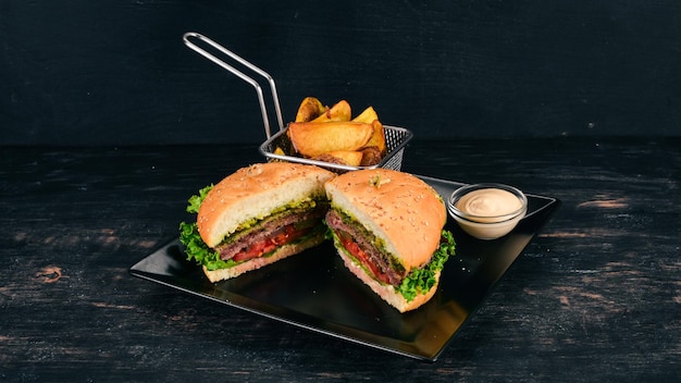 Patatas al horno y hamburguesa con carne, tomates y cebollas Sobre un fondo de madera Espacio libre para texto Vista superior