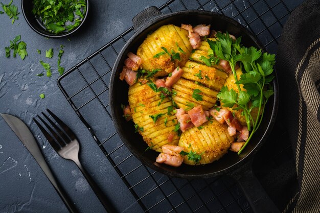 Patatas al horno con jamón, hierbas y pan rallado sobre superficie oscura. Cocina escandinava. Vista superior.