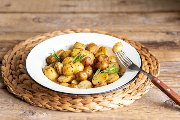 Patatas al horno jóvenes con romero. Hornee en el horno y fría las papas jóvenes en una sartén. Papas pequeñas con mantequilla y hierbas. Un concepto de comida rústica. Papas fritas.