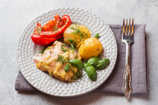 Patatas al horno con pollo y verduras en un plato.