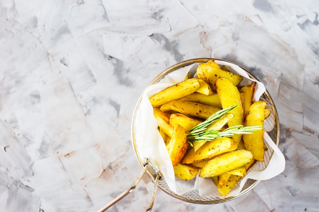 Patatas al horno en rodajas con especias y romero en una rejilla para freír