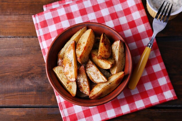 Patatas al horno en un tazón y salsa en la mesa de cerca