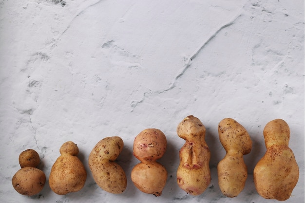 Patatas anormales orgánicas feas en la superficie de mármol, concepto de verduras orgánicas, espacio de copia