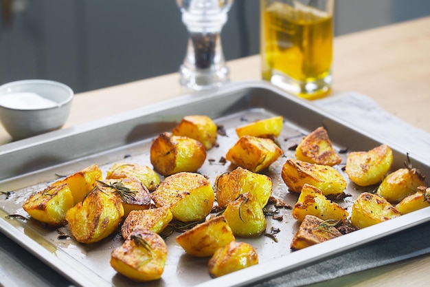 Patatas asadas en la bandeja para hornear con ajo y romero en la mesa de la cocina