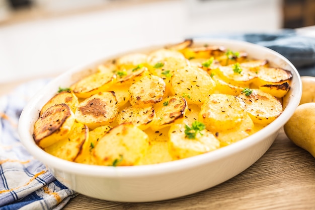 Patatas asadas con especias y hierbas en la mesa de la cocina.