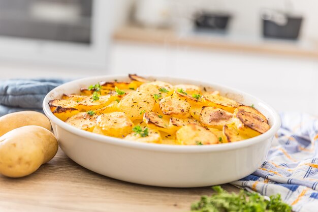 Patatas asadas con especias y hierbas en la mesa de la cocina.