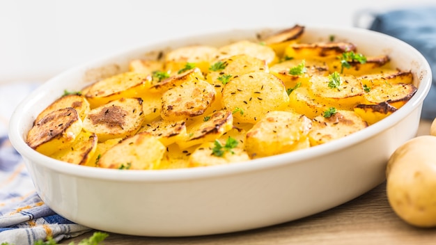 Patatas asadas con especias y hierbas en la mesa de la cocina.