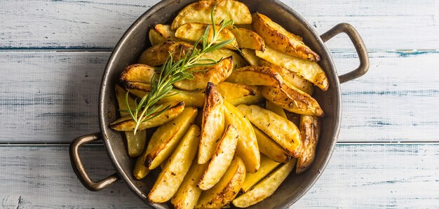 Patatas asadas en una sartén sobre plancha de madera.