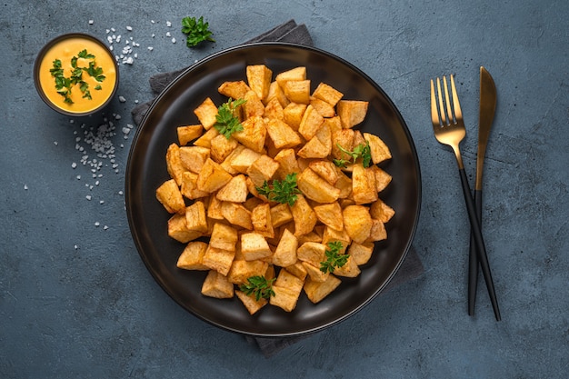 Patatas Bravas ist ein traditioneller spanischer Snack auf grauem Hintergrund. Blick auf die Super, Nahaufnahme.