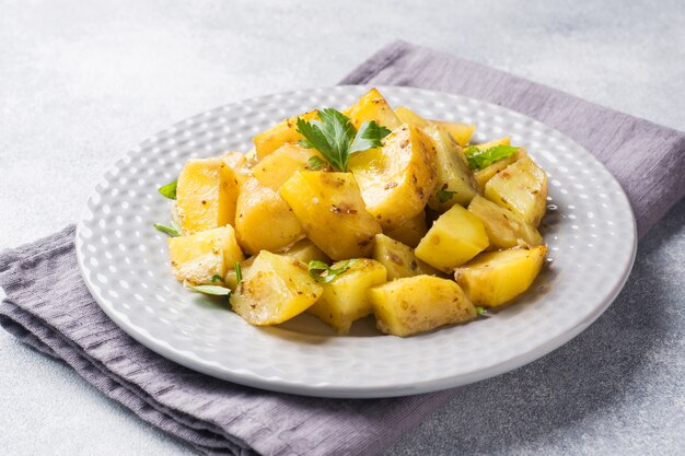 Patatas cocidas con las especias y las hierbas en una placa.