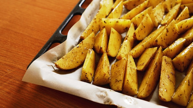 Foto patatas crudas en rodajas en una bandeja para hornear con especias y romero, vista superior, espacio de copia