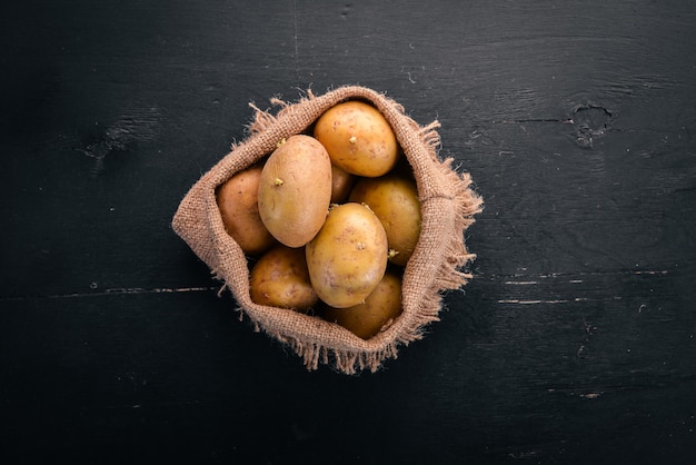 Patatas crudas sobre un fondo de madera negra Cocinar Espacio libre para texto Vista superior