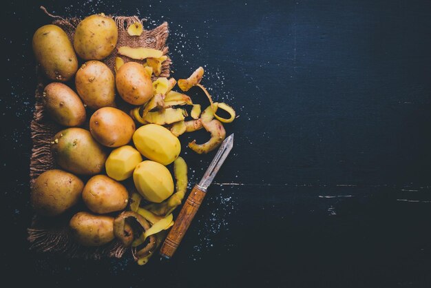 Patatas crudas sobre un fondo de madera negra Cocinar Espacio libre para texto Vista superior