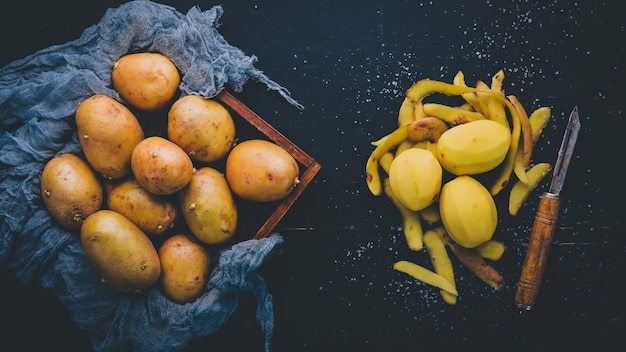 Patatas crudas sobre un fondo de madera negra Cocinar Espacio libre para texto Vista superior