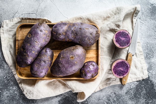 Foto patatas crudas en una tabla de cortar. vista superior.