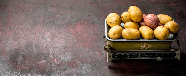 Patatas frescas en la balanza sobre una mesa rústica.