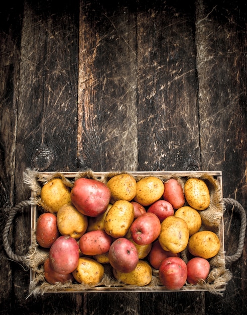 Patatas frescas en una bandeja vieja. Sobre un fondo de madera.