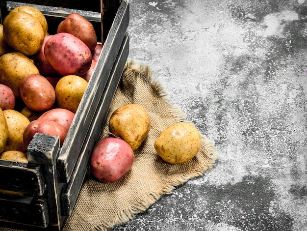 Patatas frescas en una caja. Sobre un fondo rústico.
