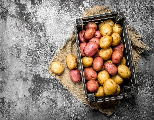 Patatas frescas en una caja. Sobre un fondo rústico.