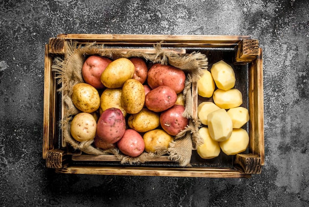 Patatas frescas en una caja. Sobre una mesa rústica.