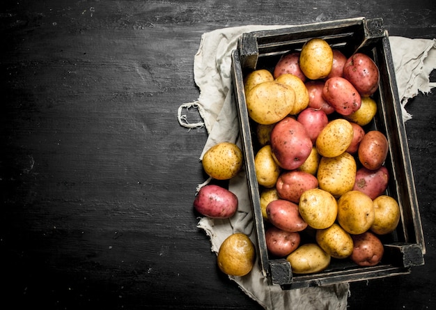 Patatas frescas en una caja vieja. En la pizarra negra.