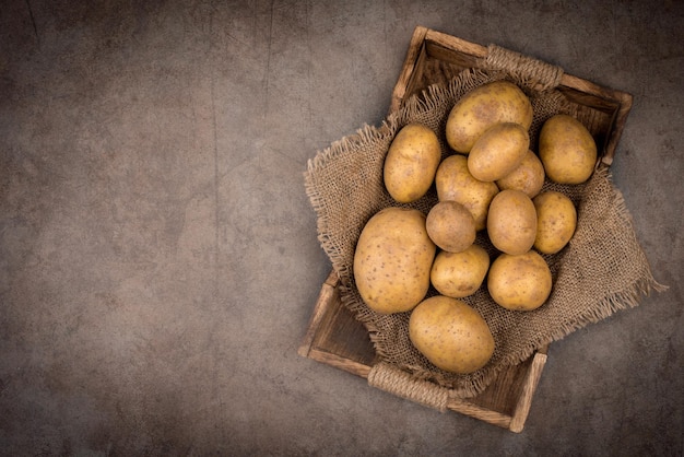 Patatas frescas sin cocer sobre un fondo de textura oscura