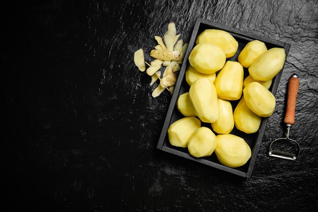 Foto patatas frescas peladas sobre un fondo negro