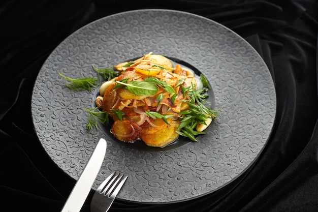 Foto patatas fritas con ajo y hierbas en un plato negro