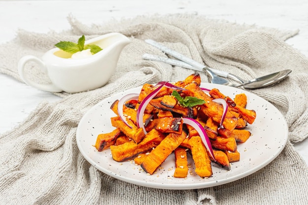 Patatas fritas de batata orgánicas al horno con especias y salsa Porción servida de vegetales dulces y cubiertos