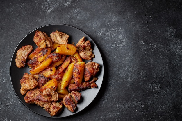 Patatas fritas con carne, en un plato negro