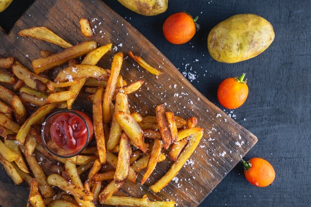 Patatas fritas caseras al horno con salsa de tomate sobre fondo de madera