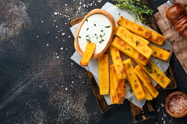 Foto patatas fritas caseras de polenta con sal marina, parmesano, tomillo, romero con salsa de yogur