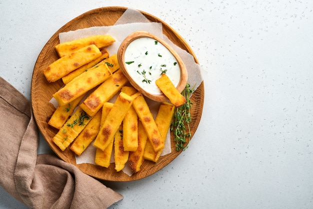 patatas fritas caseras de polenta con sal marina, parmesano, tomillo, romero con salsa de yogur