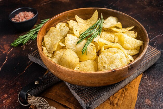 Patatas fritas caseras con sal marina y romero en plato de madera Fondo oscuro Vista superior