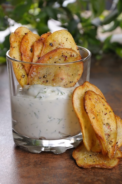 Foto patatas fritas caseras y salsa picante servida en vaso.