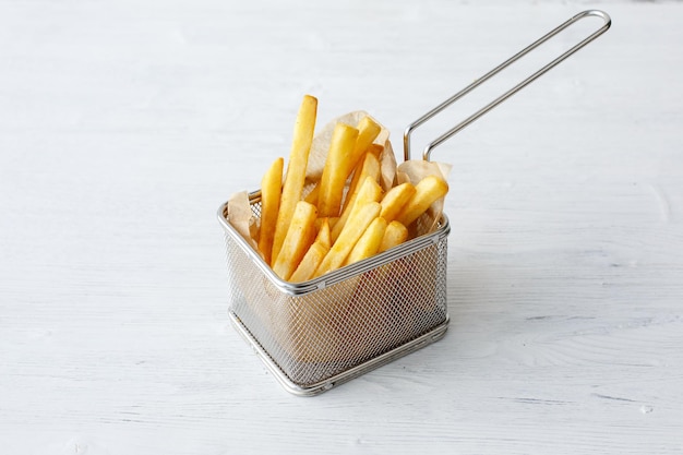 Patatas fritas en una cesta de comida rápida sobre un fondo blanco.