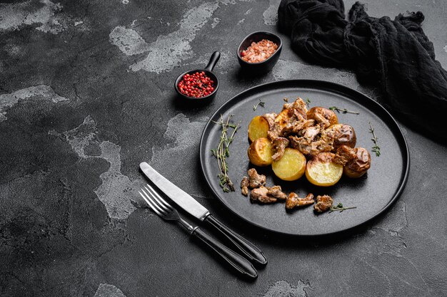 Patatas fritas con champiñones rebozuelos, sobre fondo de mesa de piedra oscura negra