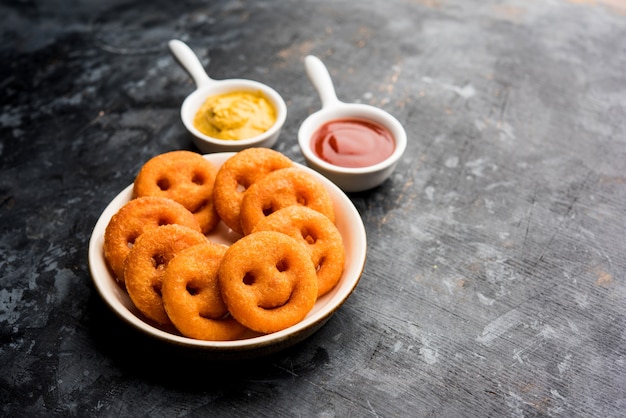 Patatas fritas crujientes con cara sonriente o bocadillos fritos con cara sonriente servidos con salsa de tomate