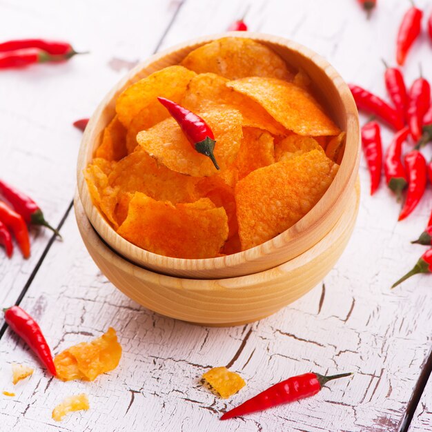 Patatas fritas crujientes con paprika en un cuenco de madera en el fondo de madera blanco