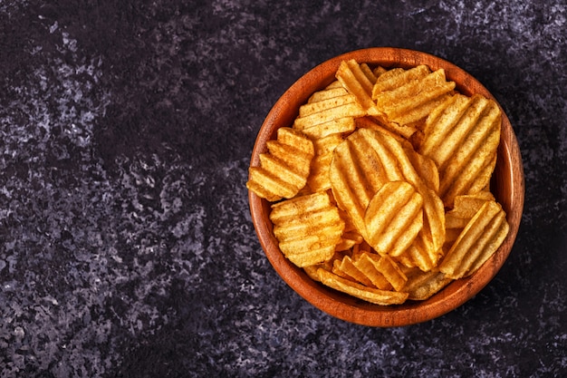 Patatas fritas crujientes en un recipiente sobre la superficie de piedra