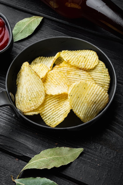 Patatas fritas crujientes. Rodajas de patata, asadas con sal marina, en madera negra