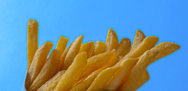 Patatas fritas crujientes sobre fondo azul.