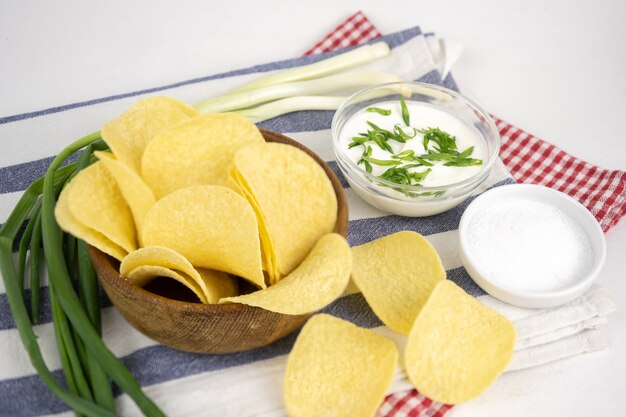 Patatas fritas en un cuenco de madera con crema agria y cebolla verde