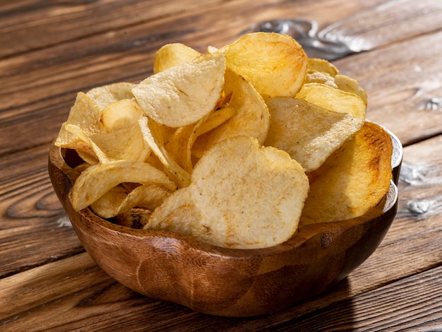 Patatas fritas en un cuenco de madera sobre fondo de madera