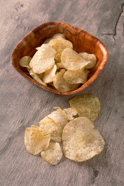 Patatas fritas en un cuenco de madera sobre fondo de madera