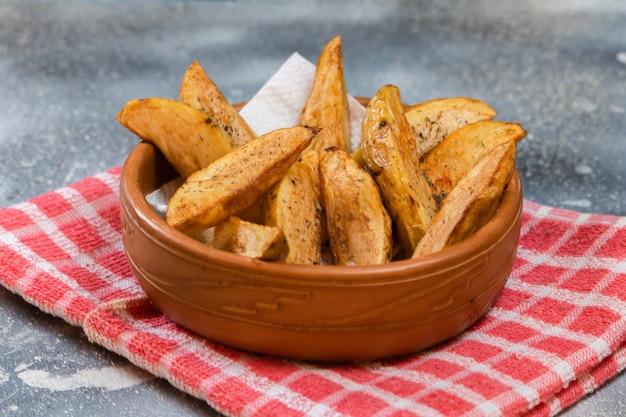 Foto patatas fritas de estilo rústico o campestre con hierbas en un recipiente de cerámica sobre una superficie de hormigón