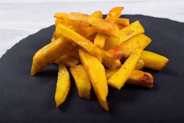 Patatas fritas fritas sobre un fondo de madera de placa de pizarra negra