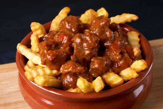 Patatas fritas con goulash en un plato rojo