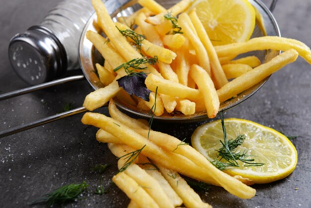 Patatas fritas con limón y sal en tamiz en primer plano de la mesa